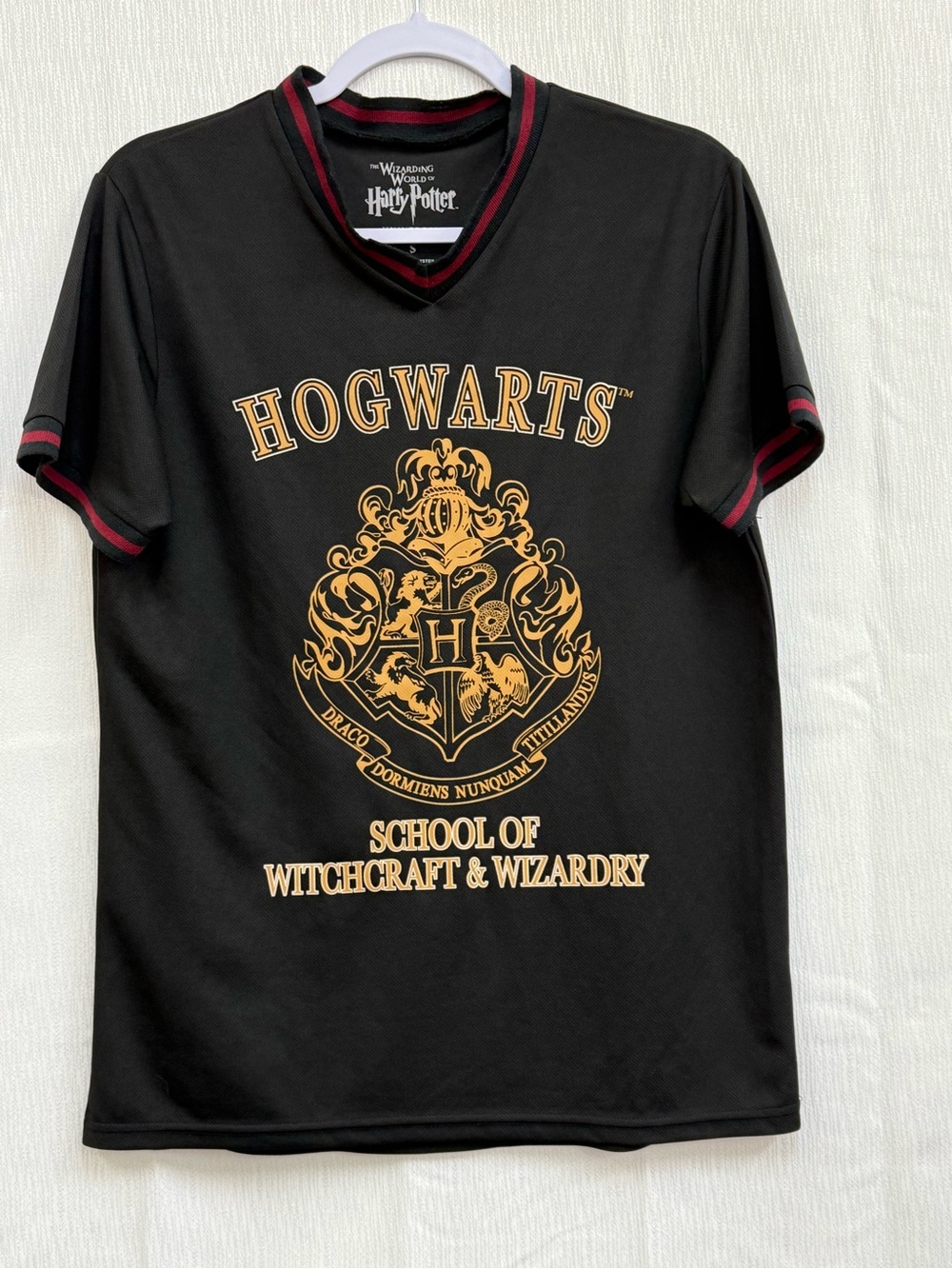 Harry Potter Tee
Hogwarts Crest V‑Neck Tee in Black with Gold and Red Trim